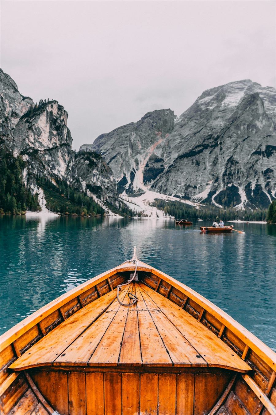 The prow of a wooden boat heading across a mountain lake